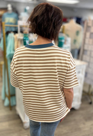 Model wearing white and tan striped top with blue collar trim