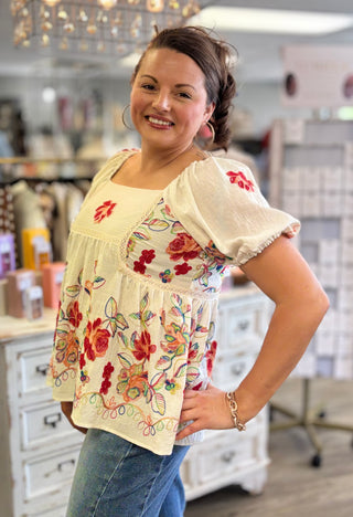 Woman wearing a floral embroidered top in a store setting
