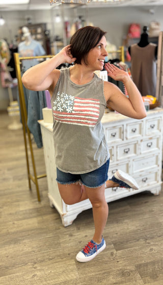 Woman wearing a gray tank top with an American flag design in a store setting.