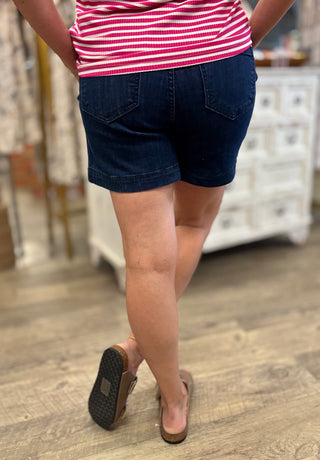 Person wearing dark denim shorts and a red and white striped shirt in an indoor setting.
