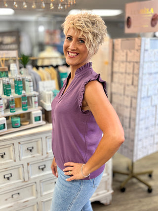 Woman in a purple top and jeans standing in a store.