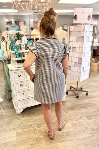 Model wearing navy and white gingham dress with sandals