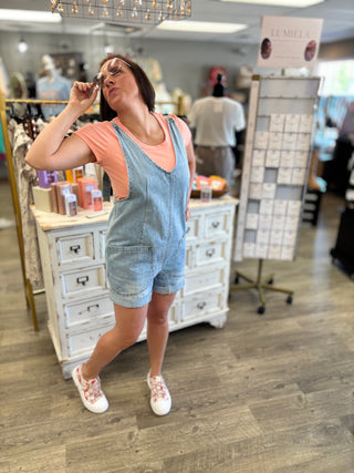 Model wearing denim short-alls and coral tee in a short setting
