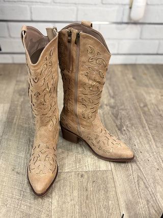 A pair of taupe colored boots with unique stitching and zipper detail
