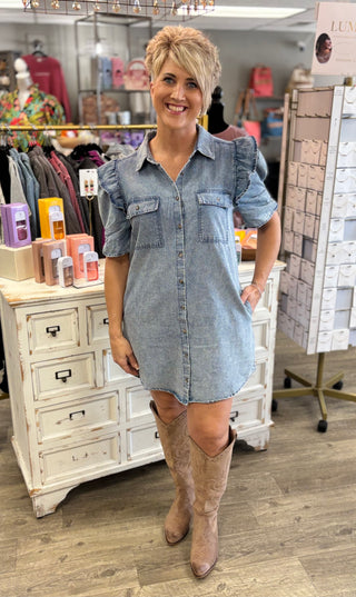 Woman wearing a denim dress and knee-high boots in a store setting