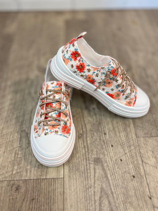 Pair of peach and white floral printed sneakers with rhinestone laces