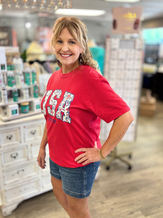 Woman wearing a red 'USA' t-shirt in a store setting