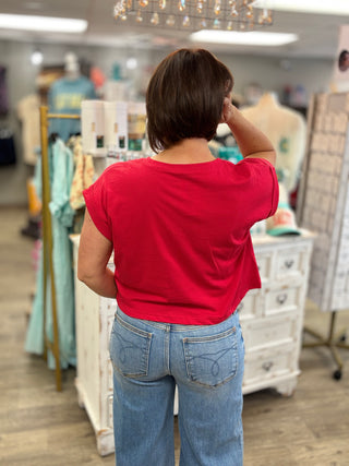 Person wearing a red shirt and blue jeans in a store setting