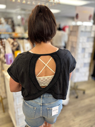 Model wearing black open back top and denim shorts