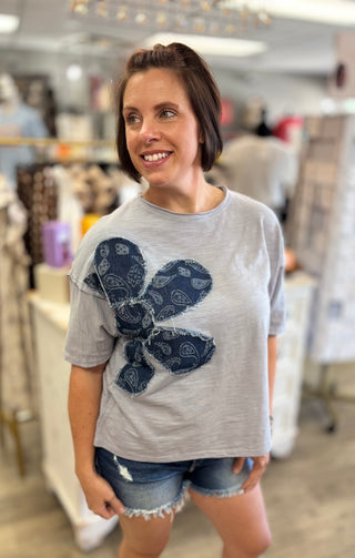 Woman wearing a blue t-shirt with a blue floral design in a store setting