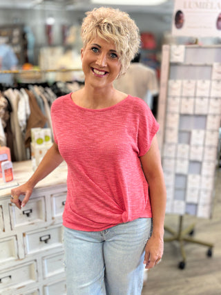 Woman wearing a pink shirt and light blue jeans standing in a store.