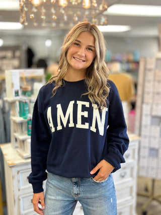 Model wearing a navy sweatshirt with “AMEN” embroidered on the front