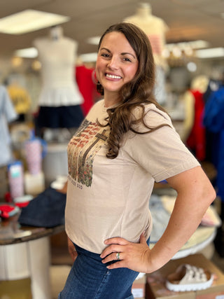 Woman wearing a beige t-shirt with a graphic design in a clothing store.