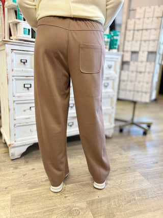 Model wearing mocha pants with back pocket detail.