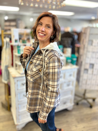 Model wearing brown, cream, and blue shacket with hood and jeans