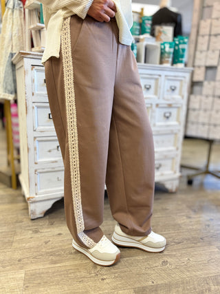 Model wearing mocha pants with cream lace details.