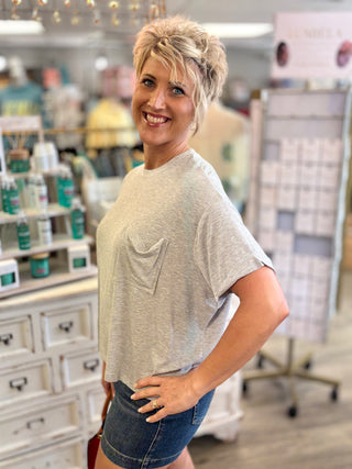 Woman wearing a gray t-shirt with a pocket in a store setting