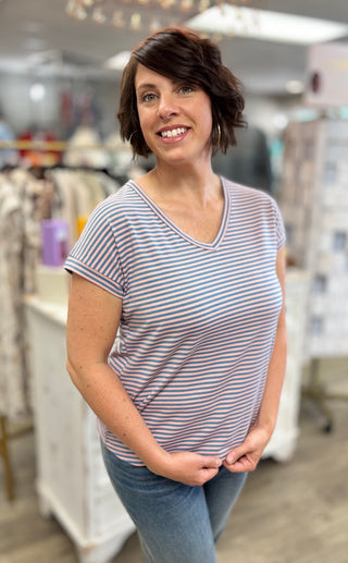 Model wearing pink and blue striped shirt in store setting