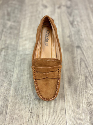 A single camel color suede penny loafer shown from a top-down view on a gray wood-look floor. 