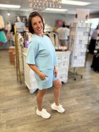 Woman in light blue outfit standing in a store.