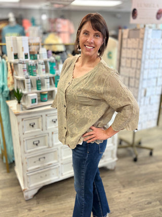 Model wearing a taupe eyelet detailed top with buttons and denim jeans