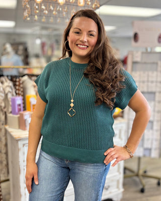 Model wearing teal green sweater with denim jeans