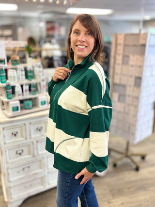 Model wearing hunter green and cream striped top with zipper detail