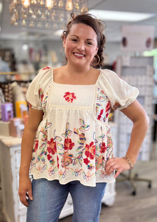 Woman wearing a floral embroidered top in a store setting