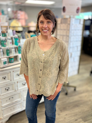 Model wearing a taupe eyelet detailed top with buttons and denim jeans