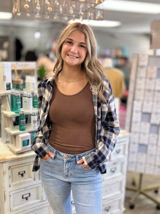 Model wearing a brown tank with navy plaid flannel and jeans