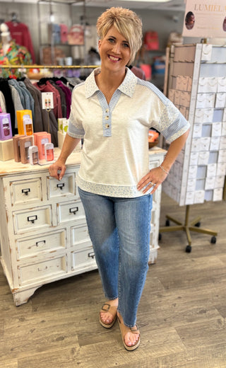 Woman wearing a white and blue striped shirt and blue jeans standing in a store.