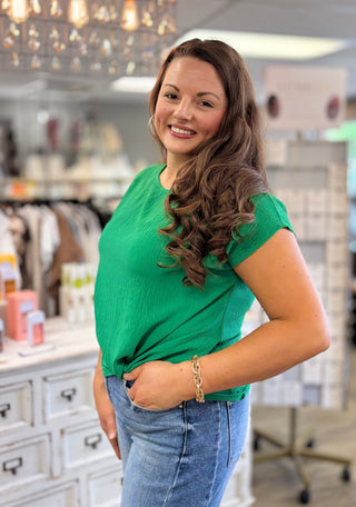 Woman wearing a green top and blue jeans in a store setting