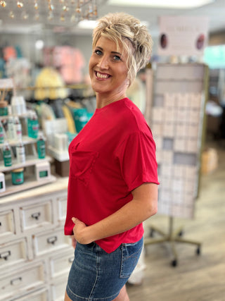 Woman in a red shirt standing in a store setting