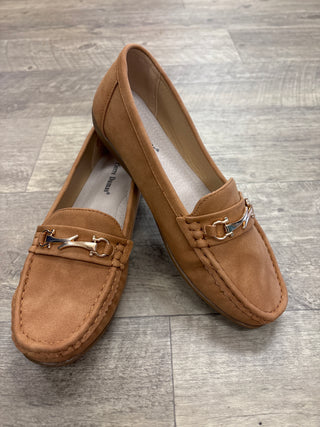 Pair of brown loafers with decorative charm on a wooden floor.