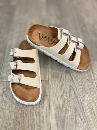 Pair of cream colored, triple buckle, platform sandals on wooden floor