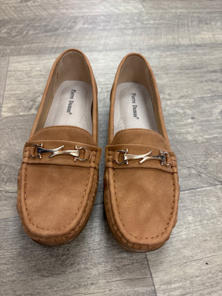 Pair of brown loafers with decorative charm on a wooden floor.
