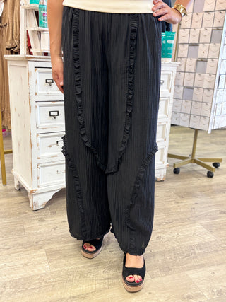 Model wearing black textured pants with a cream top and peep toe wedge shoes