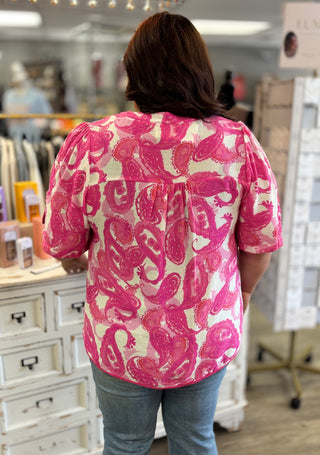 Person wearing a pink and white patterned blouse in a store setting