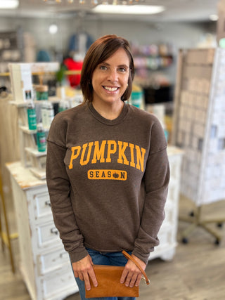 Model wearing a brown sweatshirt with ‘Pumpkin Season’ graphic