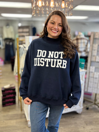 Model wearing navy mock neck sweatshirt with DO NOT DISTURB graphic