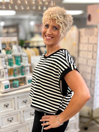 Model wearing black and white striped short sleeve top with key hole back detail