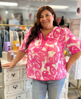 Woman wearing a pink and white patterned blouse in a store setting