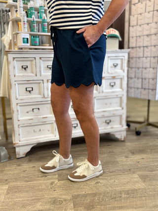 Model wearing navy shorts featuring scalloped edge and functional drawstring 