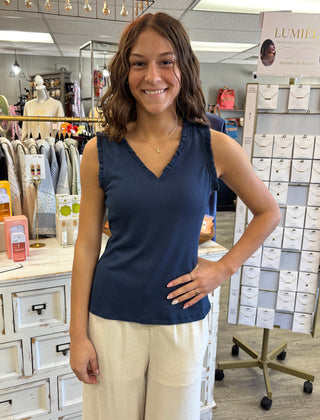 Woman wearing a navy sleeveless top and beige pants in a store setting