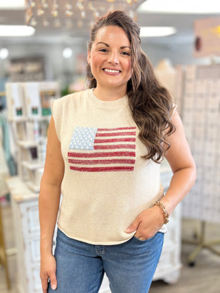 Woman wearing a sleeveless beige top with an American flag design in a store setting.