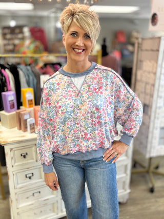 Woman wearing a floral sweater and jeans in a store setting