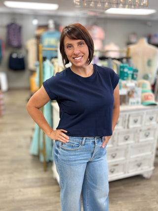 Woman wearing a navy blue top and light blue jeans in a store setting