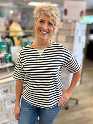 Model wearing white and navy striped top with tan collar trim