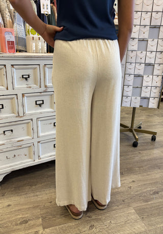 Person wearing a navy top and beige wide-leg pants in an indoor setting.