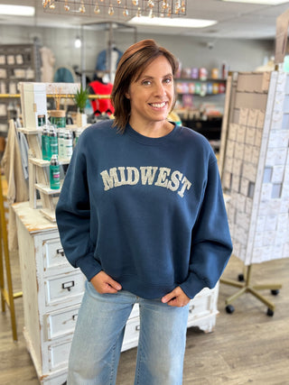 Front view of the Midwest Cozy Sweatshirt, a dark blue crewneck with raised grey MIDWEST lettering and full balloon sleeves